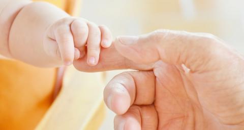 infant holding man's finger